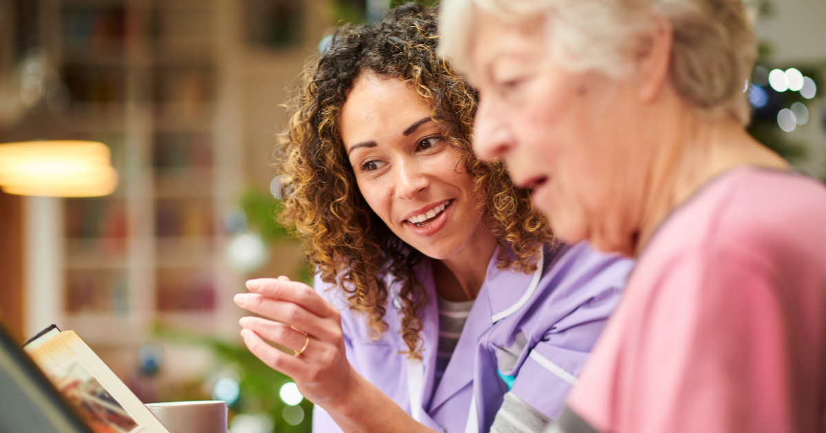 Senior woman and caregiver looking at a family album together