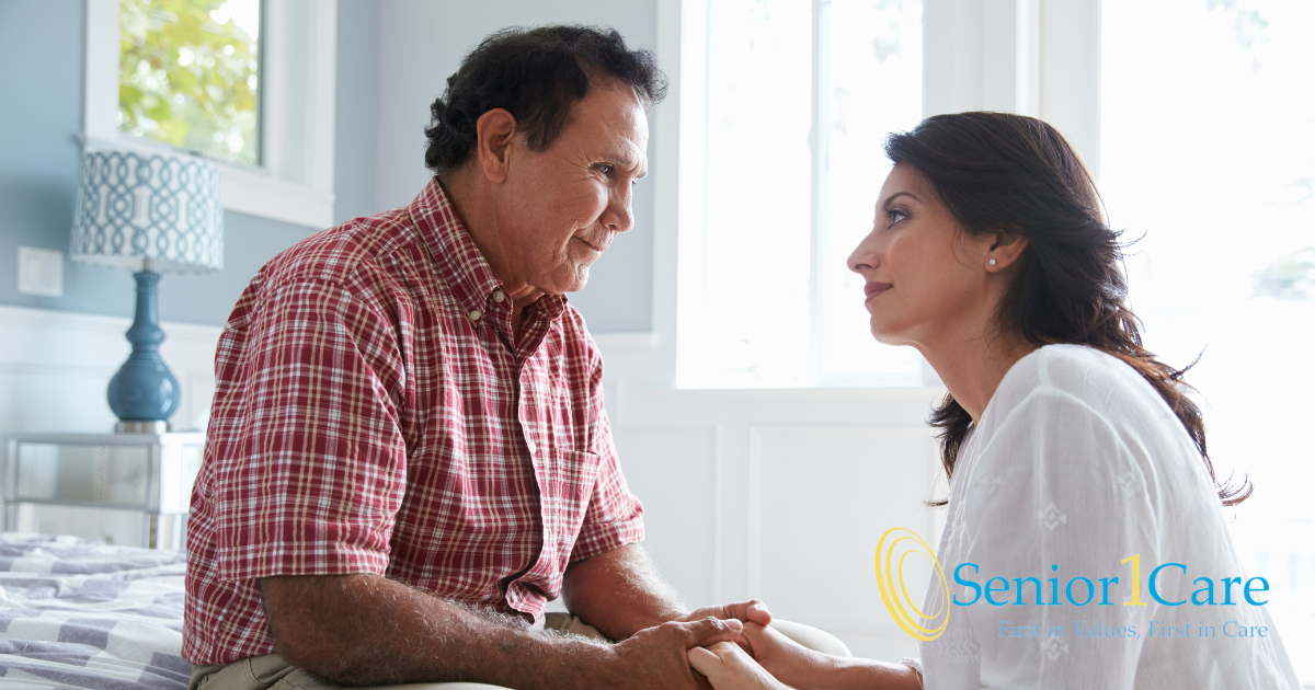 A daughter who is caregiving for her dad who has Alzheimer’s disease, lovingly holds his hands.