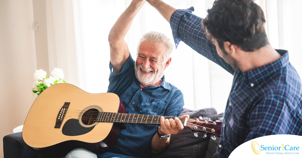 A smiling son high fives his happy elderly father as he plays the guitar, showing the positive effect music can have on people, including those with dementia.