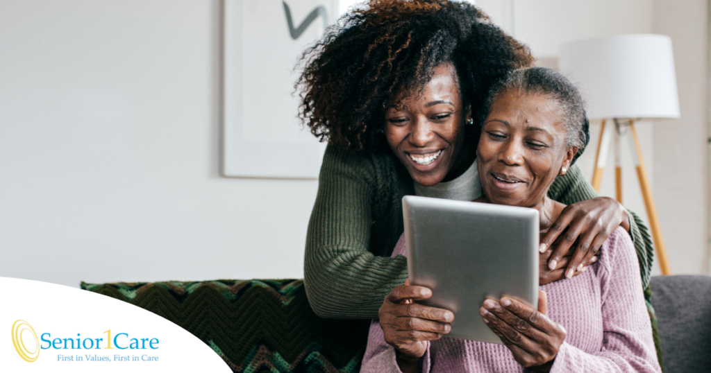 A caregiver helps a senior with her tablet, representing the rise of technology in home care.