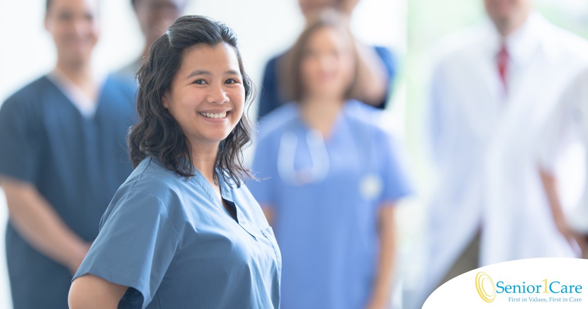 A woman in scrubs smiles with a team behind her, representing the joy that can come from a career as an OT, as Occupational Therapy Month promotes.