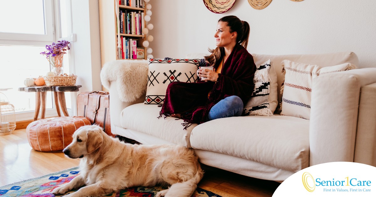 A woman relaxes with her dog while sipping on tea, representing how self-care can combat caregiver stress.