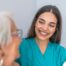 A caregiver smiles with an older client showing the results of successfully starting a new caregiving job.