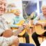 A compassionate young caregiver with a stethoscope around her neck gently looks after an elderly woman sitting on a couch, showing the warmth and connection possible through in-home care.