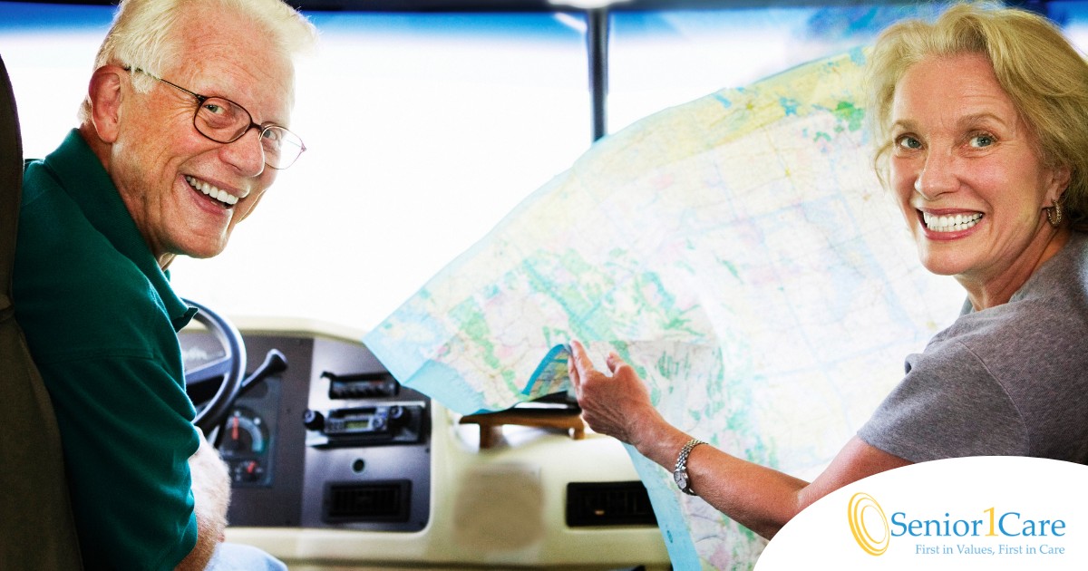 An older couple looks back smiling from the front of an RV, representing how day trips for seniors can help boost the mood of everyone.