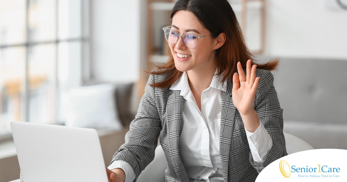 A well-dressed woman smiles and says hi on a videoconference, representing a candidate who is well-prepared for a caregiver interview.