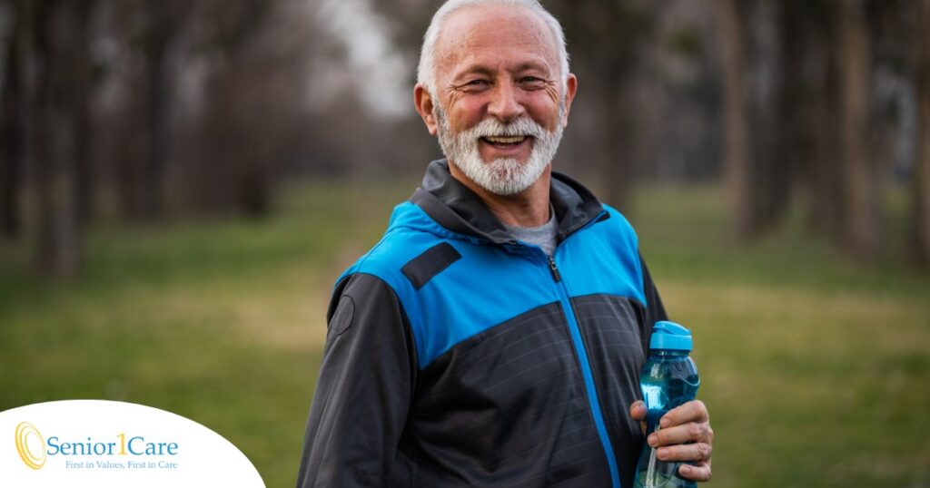 An older man smiles with a water bottle while exercising, representing the benefits of encouraging exercise when caring for seniors at home.