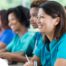 Several students in scrubs happily attend a class, representing caregiver training.