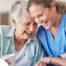 A woman in scrubs laughs with a senior woman, representing how caregiving can be a great career choice.