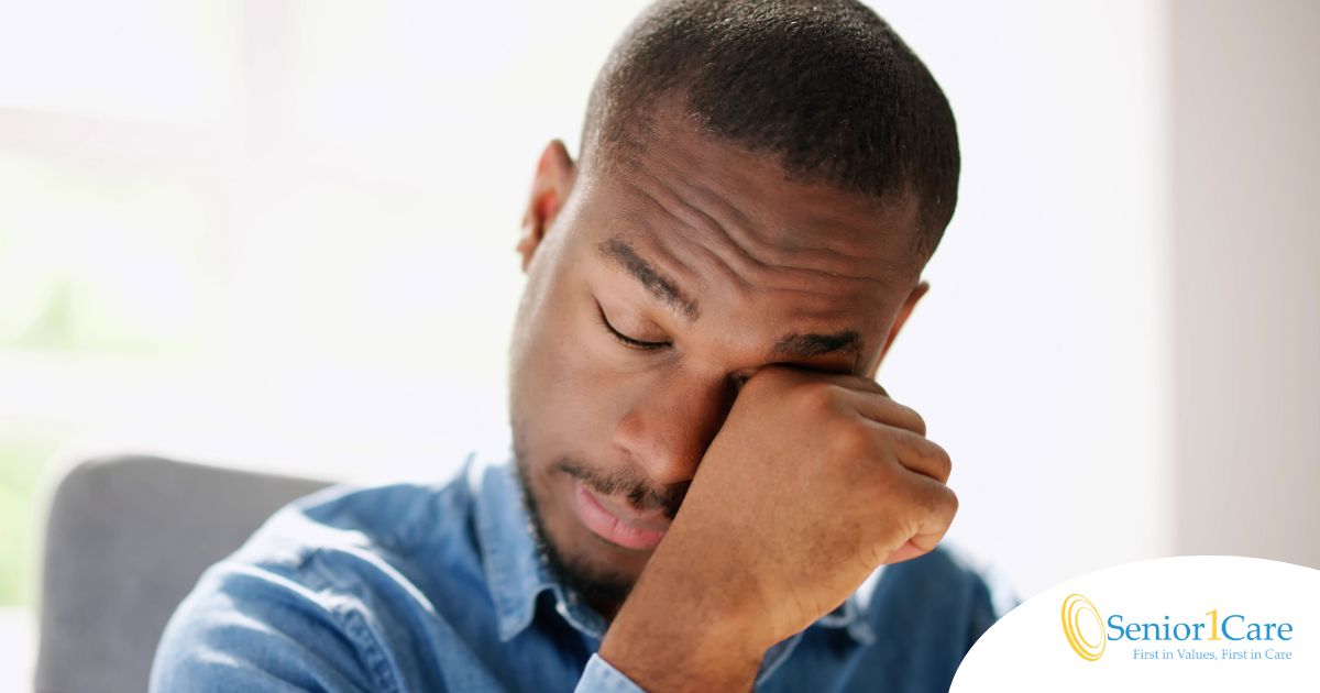 A man tiredly rubs his eyes, representing the exhaustion that can come with family caregiving.