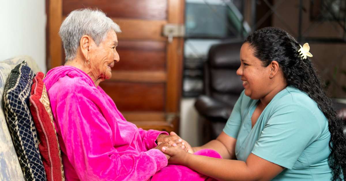 A Senior1Care caregiver providing companionship to an elderly woman at home in Mishawaka, offering emotional support and meaningful conversation.