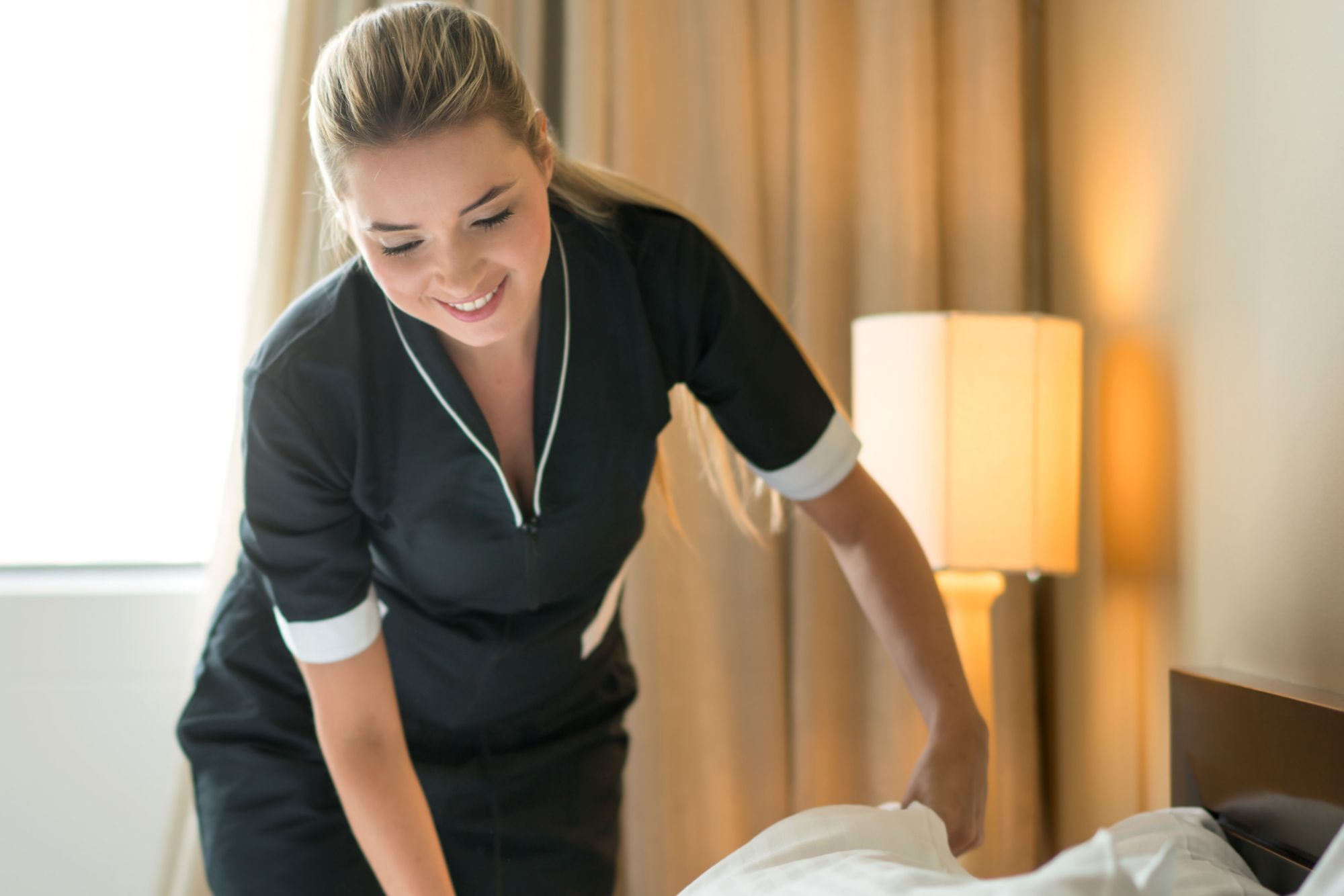 Senior1Care caregiver assisting with light housekeeping by preparing clean bedding in a senior’s home in Goshen, IN.