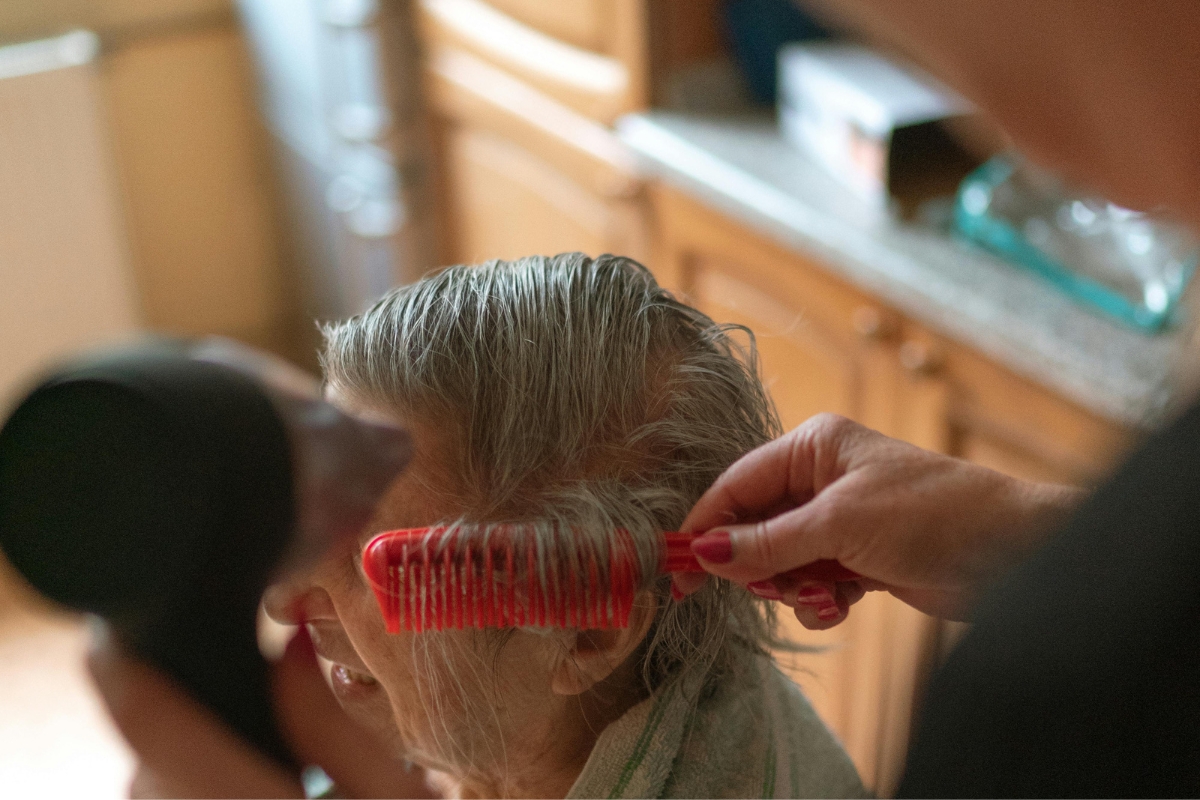 Senior1Care caregiver helping an elderly woman with hair care at home in Goshen.