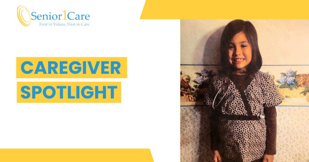A young girl smiling while wearing a toy stethoscope and patterned scrubs, standing against a floral wallpaper background. The text “Caregiver Spotlight” appears beside her along with the Senior1Care logo.