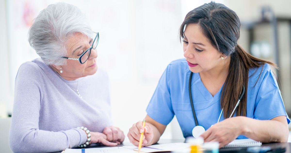 A professional caregiver reviews medication instructions with an elderly woman to ensure safe and accurate medication management in Granger, Indiana.