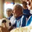 A group of joyful seniors in blue and white jerseys cheering during a World Cup match, illustrating the power of human connection fostered by Senior1Care.